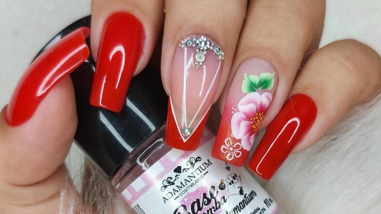 Unhas em vermelho com adesivo de flor e strass